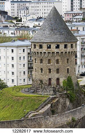 Stock Photo - Large old stone castle turret on hillside with stone wall and modern buildings in the background; Brest, Brittany, France. Fotosearch