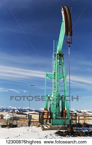 Large pump jack in a snow covered field with snow covered mountains, blue sky and clouds in the background; Longview, Alberta, Canada View Large Photo Image Stock Photograph - Large pump jack in a snow covered field with snow covered mountains, blue sky and clouds in the background; Longview, Alberta, Canada. Fotosearch