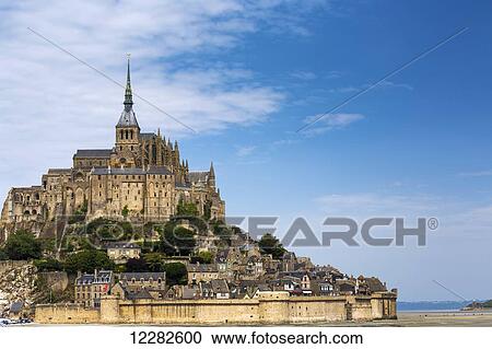 Large stone Abbey at low tide perched on a rocky island with blue sky and clouds; Mont St. Michel, Brittany, France View Large Photo Image Stock Image - Large stone Abbey at low tide perched on a rocky island with blue sky and clouds; Mont St. Michel, Brittany, France. Fotosearch