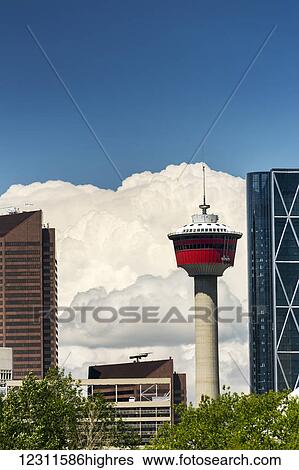 Stock Photograph - Large white thunderstorm clouds and blue sky with the Calgary Tower and city buildings in the foreground; Calgary, Alberta, Canada. Fotosearch