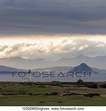 Stock Photograph - Lighthouse and mountains along the coastline at Trump Turnberry Golf Resort; Turnberry, Scotland. Fotosearch