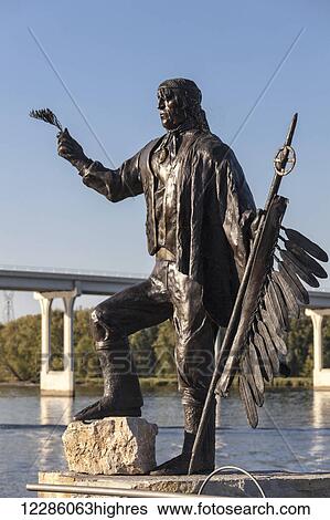 Stock Photograph - Likeness of Chief Washa II holding cedar sprig and eagle feather staff, designed and sculpted by Joanne Bird at Eagle Centre, Mississippi River Waterfront; Wabasha, Minnesota, United States of America. Fotosearch