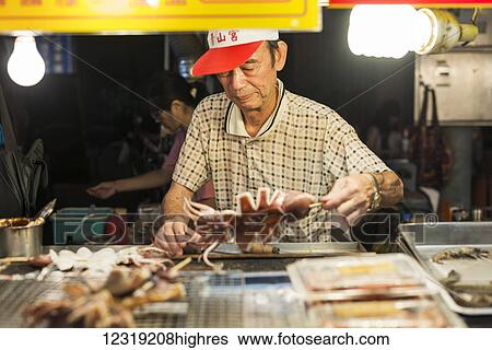 Stock Photograph - Local night markets of Taipei are really famous because it's delicious food, a male vendor preparing his specialty food; Taiwan, China. Fotosearch