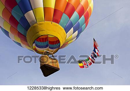 Looking up underneath a colourful hot air balloon which floats away trailing a multi-national flag tail; Ripon, California, United States of America View Large Photo Image Stock Photograph - Looking up underneath a colourful hot air balloon which floats away trailing a multi-national flag tail; Ripon, California, United States of America. Fotosearch