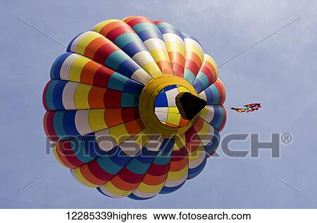 Stock Photograph - Looking up underneath a colourful hot air balloon which floats away trailing a multi-national flag tail; Ripon, California, United States of America. Fotosearch