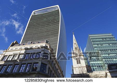 Stock Photograph - Low angle view of 20 Fenchurch Street, known as the Walkie Talkie building, and a church steeple; London, England. Fotosearch
