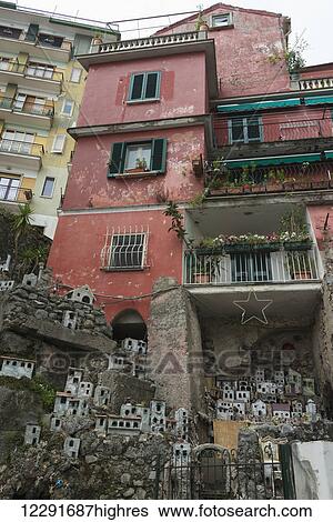 Stock Photograph - Low angle view of red and yellow residential buildings with a miniature sized display of houses in a community; Amalfi, Campania, Italy. Fotosearch