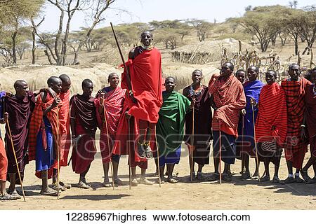 Stock Photograph - Maasai warriors wearing brightly coloured clothing perform traditional dance, Ngorongoro Crater Conservation Area; Tanzania. Fotosearch