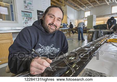 Stock Photograph - Male native artist seated at a work table carving scrimshaw on Bowhead whale baleen at the Inupiat Heritage Center, Barrow, North Slope, Arctic Alaska, USA. Fotosearch
