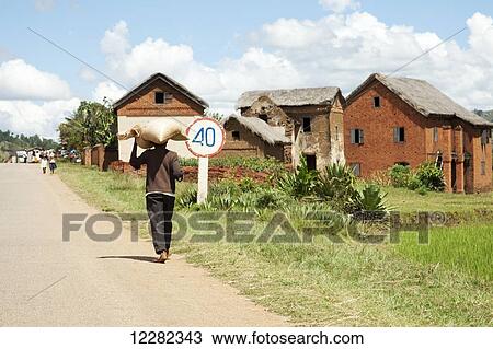 Man carrying a bag on his head in a small village; Madagascar View Large Photo Image Stock Image - Man carrying a bag on his head in a small village; Madagascar. Fotosearch