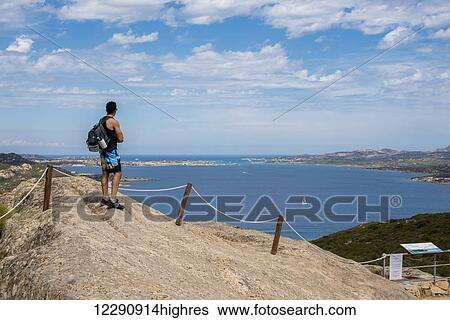 Stock Photograph - Man enjoying the panoramic view from Capo d'Orso; Palau, Sardinia, Italy. Fotosearch