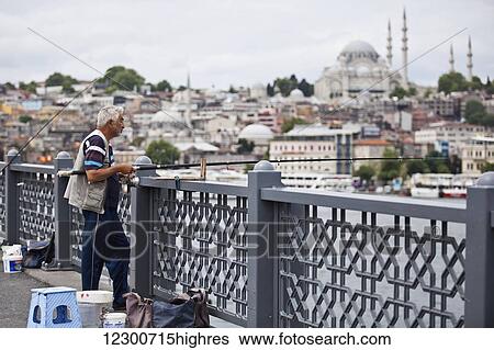 Stock Photograph - Man fishing near Sultanahmet, old city waterfront; Istanbul, Turkey. Fotosearch