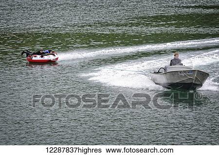 Man in skiff tows kids on a tube through Halibut Cove, Southcentral Alaska View Large Photo Image Stock Photograph - Man in skiff tows kids on a tube through Halibut Cove, Southcentral Alaska. Fotosearch