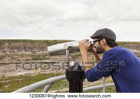Man looking through binoculars outdoors at the Royal Tyrell Museum Of Palaeontology; Drumheller, Alberta, Canada View Large Photo Image Stock Photograph - Man looking through binoculars outdoors at the Royal Tyrell Museum Of Palaeontology; Drumheller, Alberta, Canada. Fotosearch