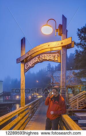 Man on a cell phone near the Creek Street sign and boardwalk on a foggy evening, downtown Ketchikan, Southeast Alaska, USA, Spring, HDR View Large Photo Image Stock Photograph - Man on a cell phone near the Creek Street sign and boardwalk on a foggy evening, downtown Ketchikan, Southeast Alaska, USA, Spring, HDR. Fotosearch