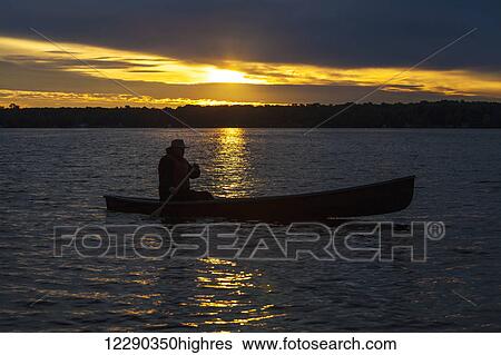 Stock Photograph - Man paddling canoe at sunrise on Balsam Lake; Ontario, Canada. Fotosearch
