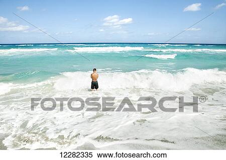 Man standing in the ocean as the waves break at the shore; Varadero, Cuba View Large Photo Image Stock Photography - Man standing in the ocean as the waves break at the shore; Varadero, Cuba. Fotosearch