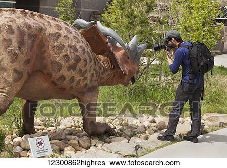 Man taking a picture of a dinosaur sculpture outdoors at the Royal Tyrell Museum of Palaeontology; Drumheller, Alberta, Canada View Large Photo Image Stock Photograph - Man taking a picture of a dinosaur sculpture outdoors at the Royal Tyrell Museum of Palaeontology; Drumheller, Alberta, Canada. Fotosearch