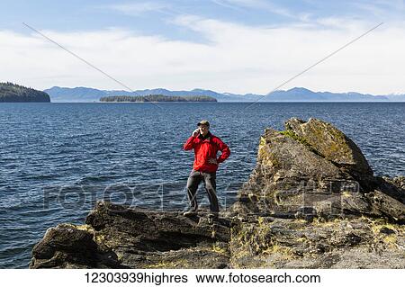 Man talks on a cell phone on a cliff above Tongass Narrows near Ketchikan, Southeast Alaska, Spring View Large Photo Image Stock Photograph - Man talks on a cell phone on a cliff above Tongass Narrows near Ketchikan, Southeast Alaska, Spring. Fotosearch