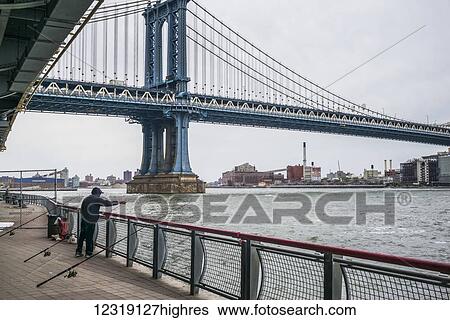 Manhattan bridge and a man standing at the railing fishing in the East river; New York City, New York, United States of America View Large Photo Image Stock Photograph - Manhattan bridge and a man standing at the railing fishing in the East river; New York City, New York, United States of America. Fotosearch
