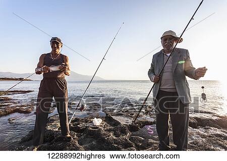 Men fishing at dusk at the water's edge of the Mediterranean, Mount Casius in the distance; Cevlik, Turkey View Large Photo Image Stock Photograph - Men fishing at dusk at the water's edge of the Mediterranean, Mount Casius in the distance; Cevlik, Turkey. Fotosearch