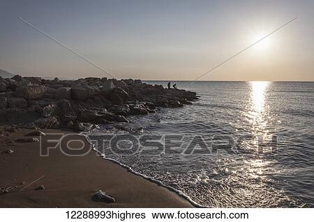 Men fishing at dusk at the water's edge of the Mediterranean, water washing onto the beach in the foreground; Cevlik, Turkey View Large Photo Image Stock Photograph - Men fishing at dusk at the water's edge of the Mediterranean, water washing onto the beach in the foreground; Cevlik, Turkey. Fotosearch