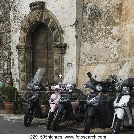 Motorcycles parked along the wall of a building with an ornate arched doorway; Positano, Italy View Large Photo Image Stock Photograph - Motorcycles parked along the wall of a building with an ornate arched doorway; Positano, Italy. Fotosearch
