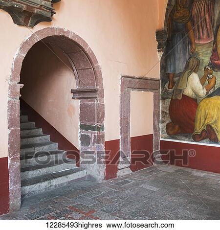Stock Photograph - Mural painted on a wall beside steps under an arch; San Miguel de Allende, Guanajuato, Mexico. Fotosearch