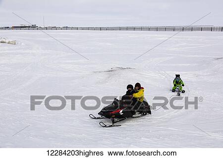 Native Alaskan youth on a snowmachine towing another behind them on sled, Barrow, North Slope, Arctic Alaska, USA, Winter View Large Photo Image Stock Photograph - Native Alaskan youth on a snowmachine towing another behind them on sled, Barrow, North Slope, Arctic Alaska, USA, Winter. Fotosearch