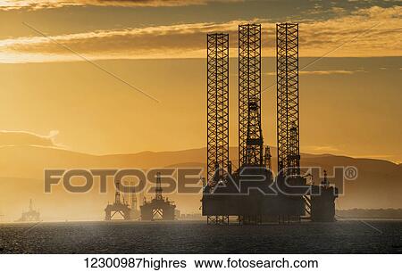 Oil drilling rigs out in the ocean with a view of the coastline and golden sunset; Cromarty, Invergordon, Scotland View Large Photo Image Stock Photograph - Oil drilling rigs out in the ocean with a view of the coastline and golden sunset; Cromarty, Invergordon, Scotland. Fotosearch