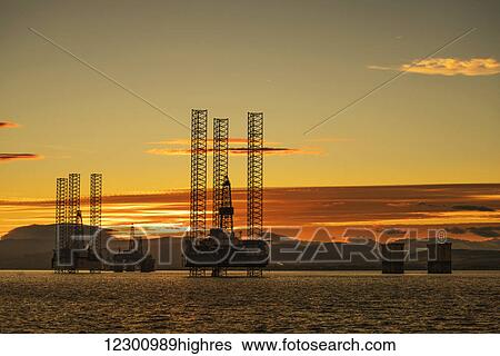 Oil drilling rigs out in the ocean with a view of the coastline and golden sunset; Cromarty, Invergordon, Scotland View Large Photo Image Stock Photograph - Oil drilling rigs out in the ocean with a view of the coastline and golden sunset; Cromarty, Invergordon, Scotland. Fotosearch