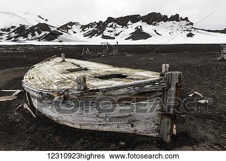 Stock Photograph - Old wooden boat abandoned on the shore at a whaling station; Deception Island, South Shetlands, Antarctica. Fotosearch