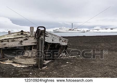 Old wooden boat abandoned on the shore at a whaling station with a cruise ship out in the water; Deception Island, South Shetlands, Antarctica View Large Photo Image Stock Photograph - Old wooden boat abandoned on the shore at a whaling station with a cruise ship out in the water; Deception Island, South Shetlands, Antarctica. Fotosearch