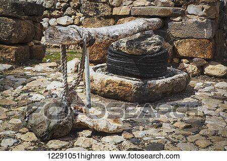 Stock Photograph - Olive press and stone basin at the site of ancient ruins; Tel Hazor, Israel. Fotosearch