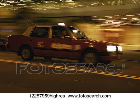 Stock Photograph - Panning shot of red Hong Kong taxi; Hong Kong, China. Fotosearch