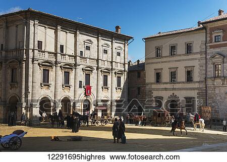 Stock Photograph - Pedestrians and horseback riders in a town square; Montepulciano, Toscana, Italy. Fotosearch