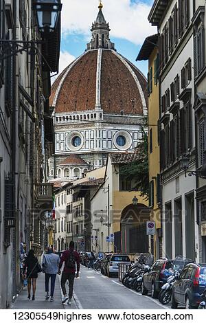 Stock Photograph - Pedestrians on a street with the dome of Florence Cathedral; Florence, Italy. Fotosearch