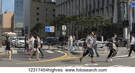 Stock Photograph - Pedestrians running across a road at a crosswalk; Seoul, South Korea. Fotosearch
