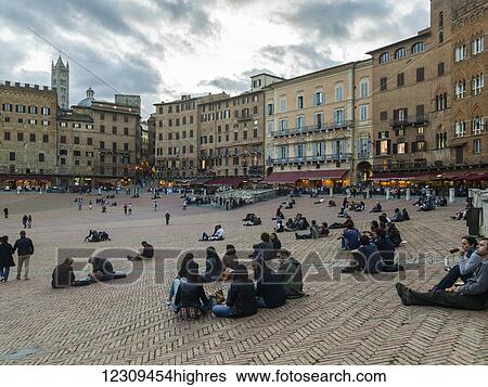 People walking and seated on the ground in a town square; Siena, Italy View Large Photo Image Stock Photograph - People walking and seated on the ground in a town square; Siena, Italy. Fotosearch