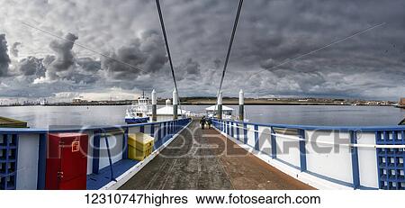 Stock Photograph - People walking on a pier out to the water and harbour; South Shields, Tyne and Wear, England. Fotosearch