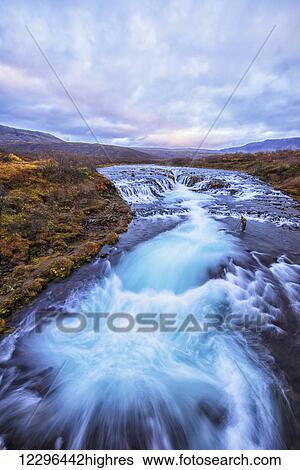 Stock Photograph - Person photographing the waterfall Bruarfoss; Iceland. Fotosearch
