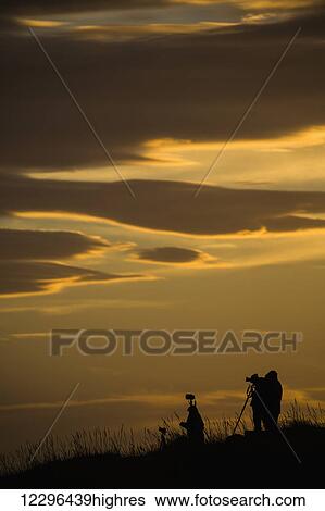 Stock Photograph - Photographers at dawn photographing the sunrise; Iceland. Fotosearch