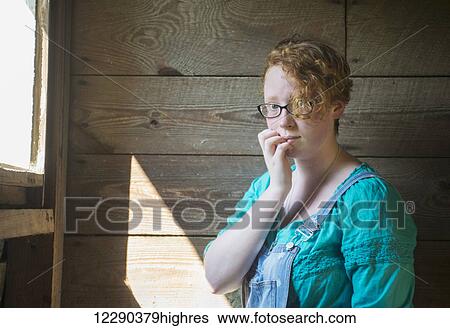 Portrait of a girl with curly red hair and eyeglasses standing against an old, wooden barn wall; Pittsboro, North Carolina, United States of America View Large Photo Image Stock Photograph - Portrait of a girl with curly red hair and eyeglasses standing against an old, wooden barn wall; Pittsboro, North Carolina, United States of America. Fotosearch