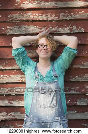 Portrait of a girl with curly red hair and eyeglasses wearing overalls and standing against an old, wooden barn wall; Pittsboro, North Carolina, United States of America View Large Photo Image Stock Photograph - Portrait of a girl with curly red hair and eyeglasses wearing overalls and standing against an old, wooden barn wall; Pittsboro, North Carolina, United States of America. Fotosearch