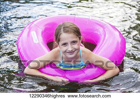 Portrait of a young girl swimming with a pink inflatable tube in a lake; Ontario, Canada View Large Photo Image Stock Photograph - Portrait of a young girl swimming with a pink inflatable tube in a lake; Ontario, Canada. Fotosearch