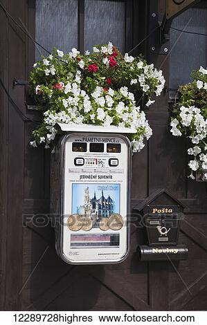 Stock Photograph - Post box and souvenir coin machine mounted on a wooden wall with flowers; Kotna Hora, Czech Republic. Fotosearch
