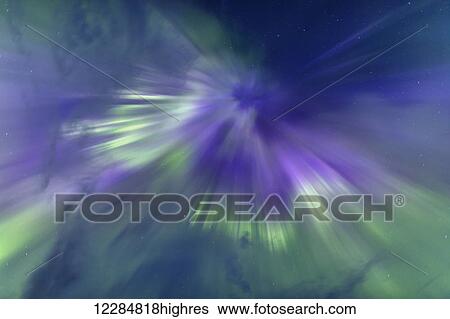 Stock Photograph - Purple and green aurora borealis form a corona overhead the Inside Passage, Southeast Alaska. Fotosearch