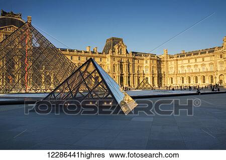 Stock Photograph - Pyramids and buildings of Le Louvre palace in golden evening light; Paris, France. Fotosearch