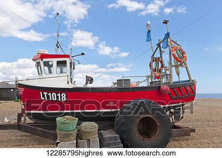 Stock Photograph - Red fishing boat on a trailer on a shingle beach; Aldeburgh, Suffolk, England. Fotosearch