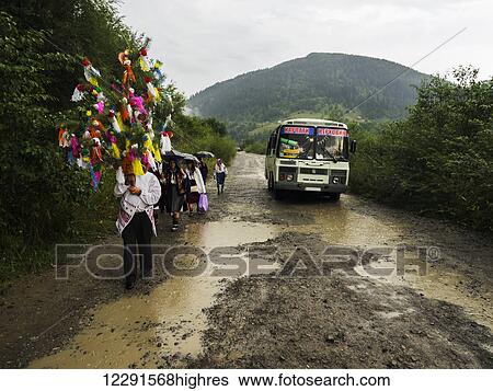 Relatives and friends escort the bride to church on the road in the rain; Kryvorivnia, Verkhovyna district, Ivano-Frankivsk region, Ukraine. View Large Photo Image Stock Photograph - Relatives and friends escort the bride to church on the road in the rain; Kryvorivnia, Verkhovyna district, Ivano-Frankivsk region, Ukraine.. Fotosearch